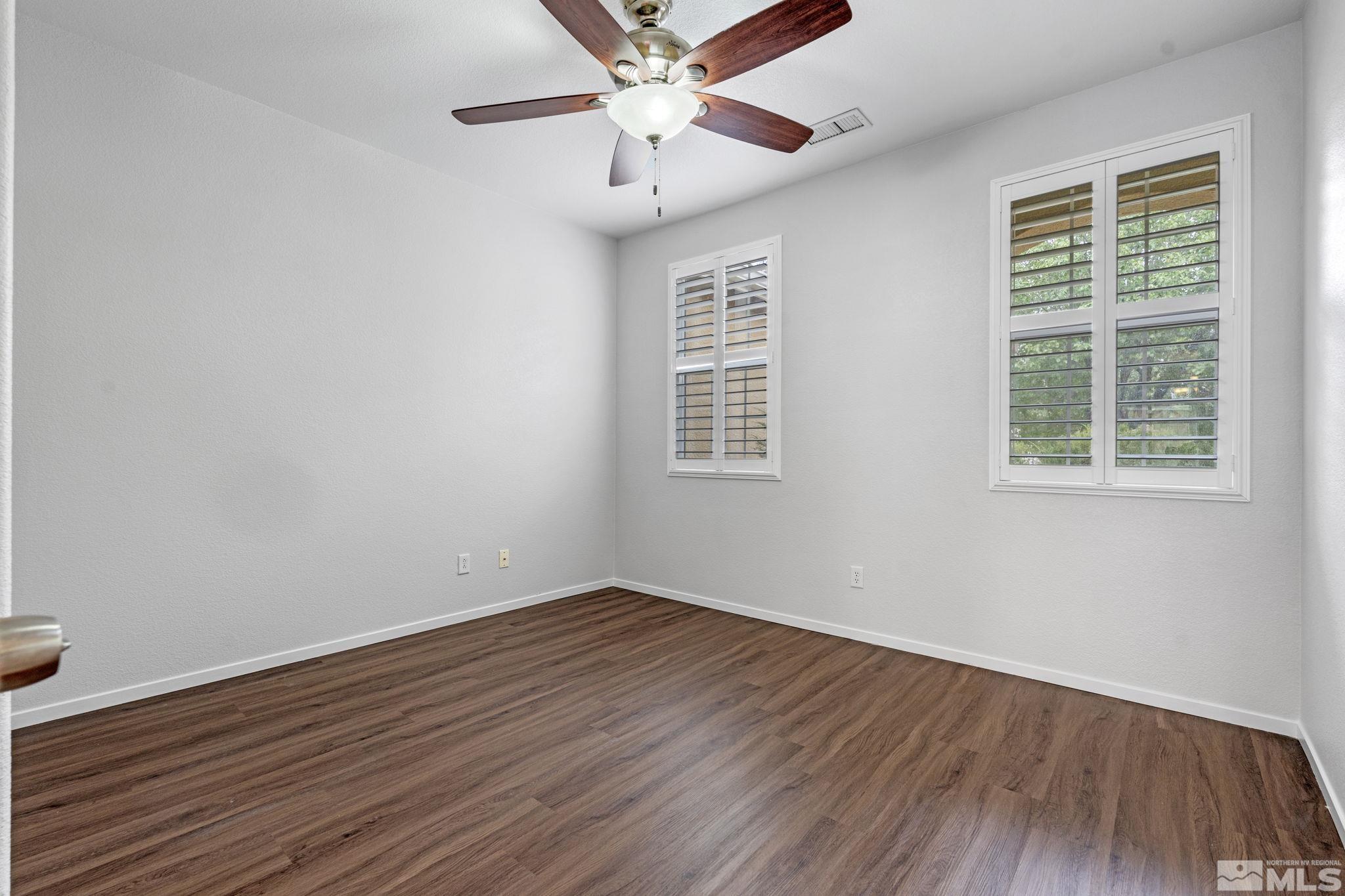 310 Pesaro Way Reno, NV 89521 - Photo 19 of 25 an empty room with wooden floor chandelier fan and windows
