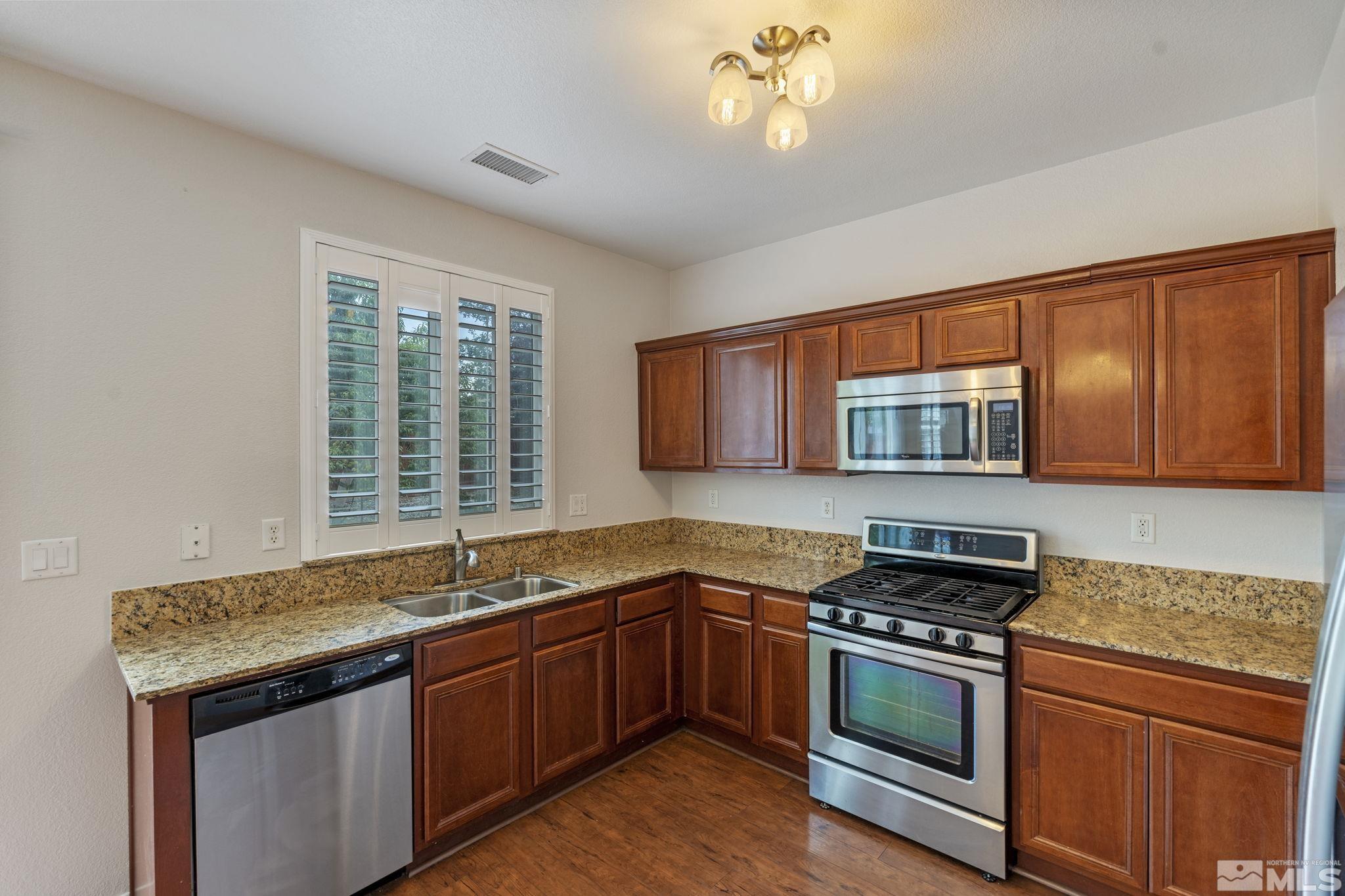 310 Pesaro Way Reno, NV 89521 - Photo 10 of 25 a kitchen with stainless steel appliances granite countertop a sink stove and cabinets