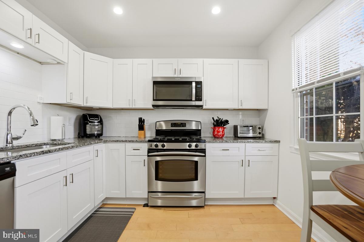 794 Quince Orchard Boulevard, Unit T2 Gaithersburg, MD 20878 - Photo 16 of 30 a kitchen with granite countertop a stove a sink and a microwave