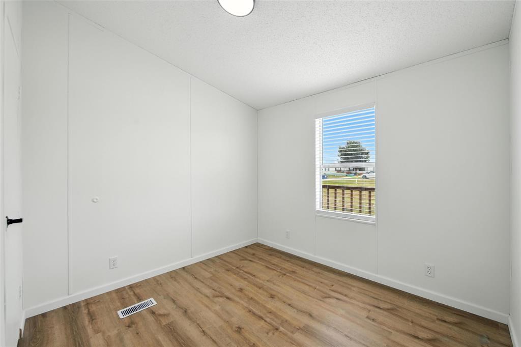197 Pondview Drive Decatur, TX 76234 - Photo 18 of 28 an empty room with wooden floor and windows
