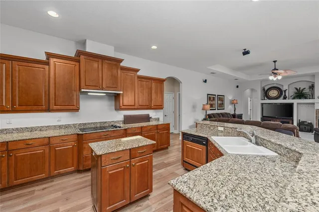 a kitchen with stainless steel appliances granite countertop a table chairs sink and cabinets
