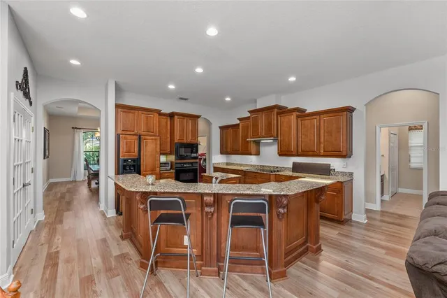 a kitchen with stainless steel appliances granite countertop a refrigerator a stove top oven dining table and chairs