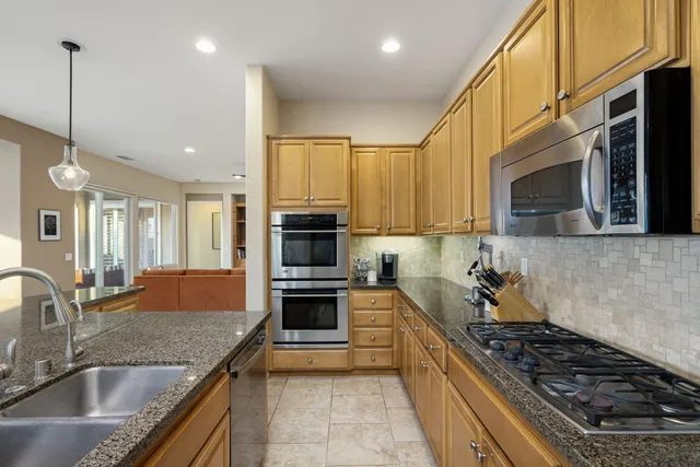 a kitchen with kitchen island granite countertop a sink and refrigerator