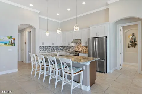 a kitchen with stainless steel appliances kitchen island granite countertop a table chairs and a refrigerator