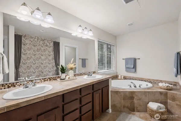 a bathroom with a tub a double vanity sink and mirror