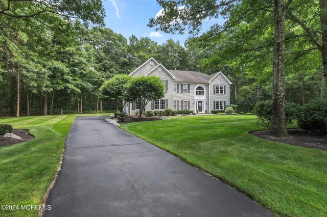 a view of a house with a big yard potted plants and large trees