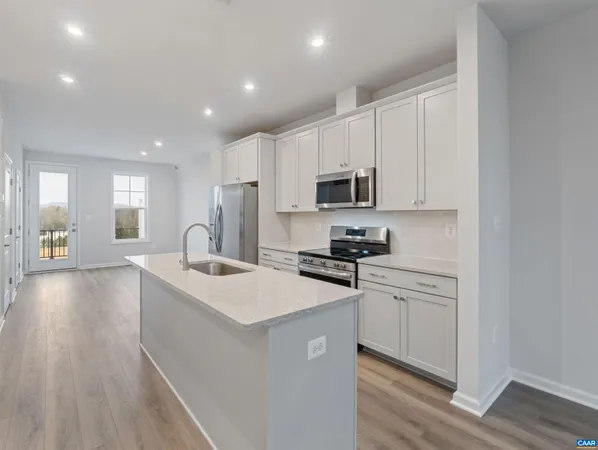 a kitchen with stainless steel appliances a sink dishwasher a stove top oven a refrigerator with white cabinets and wooden floor