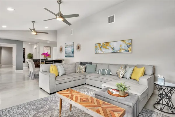 a living room with furniture kitchen view and a chandelier