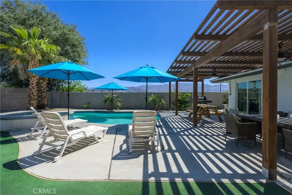 a view of patio with table and chairs under an umbrella with a barbeque