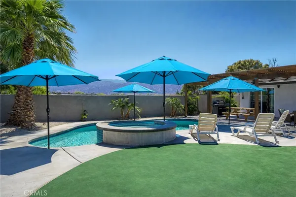 a view of a backyard with chairs under an umbrella