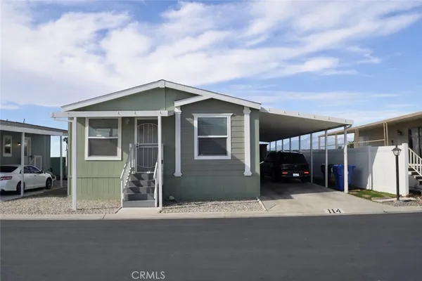 a view of a house with a barbeque and large trees
