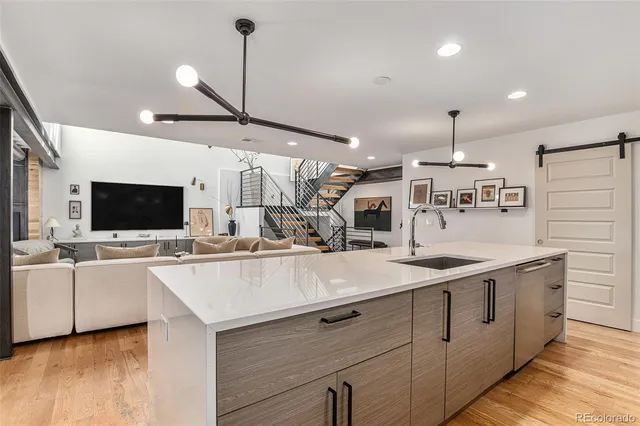 a large kitchen with a large counter space a sink appliances and living room view