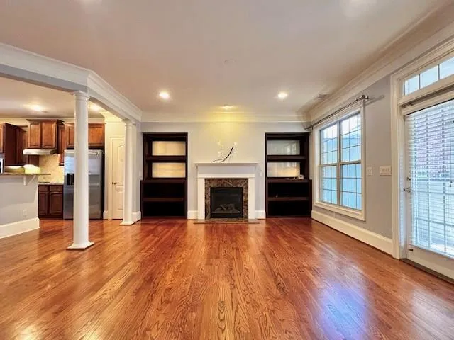 a view of a room with wooden floor fireplace and windows