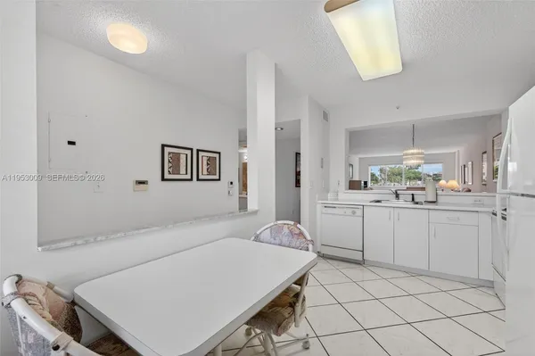 a kitchen with a sink dishwasher and white cabinets with wooden floor