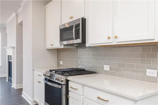 a kitchen with granite countertop white cabinets and stainless steel appliances