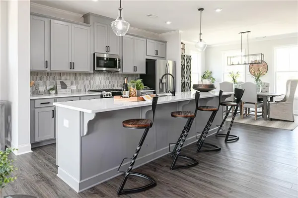 a kitchen with stainless steel appliances granite countertop a table chairs sink refrigerator and microwave