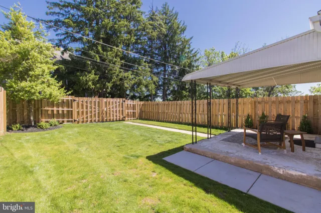 a view of a backyard with table and chairs under an umbrella with wooden fence