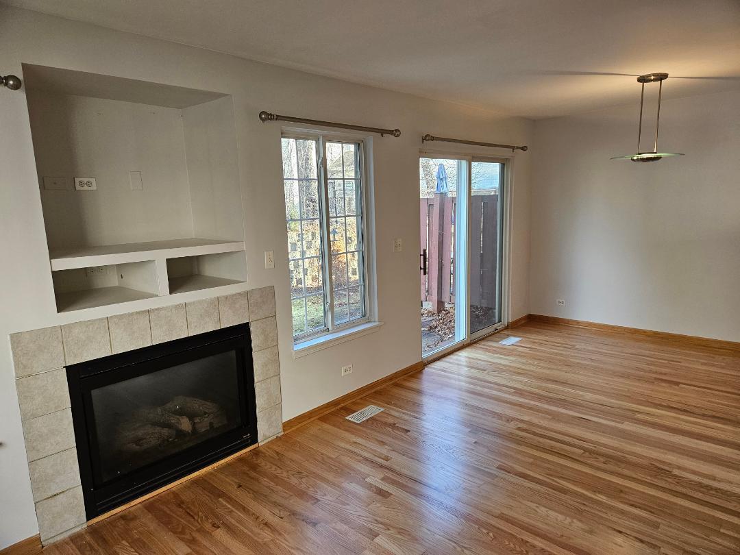 10 Ronan Court, Unit 10 Lake In The Hills, IL 60156 - Photo 5 of 20 a view of an empty room with wooden floor fireplace and a window