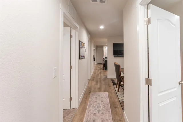 a hallway with a view of living room with wooden floor