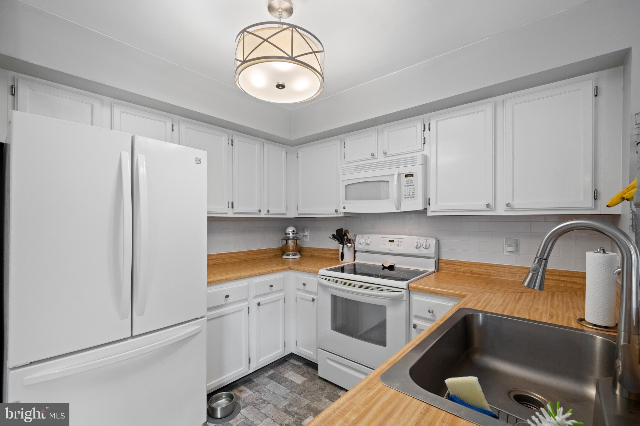 6022 Curtier Drive, Unit E Alexandria, VA 22310 - Photo 6 of 38 a kitchen with a refrigerator sink and white cabinets