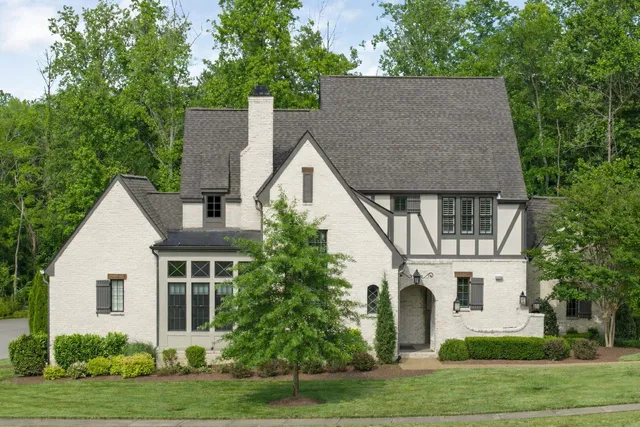 a view of house with garden and tall trees