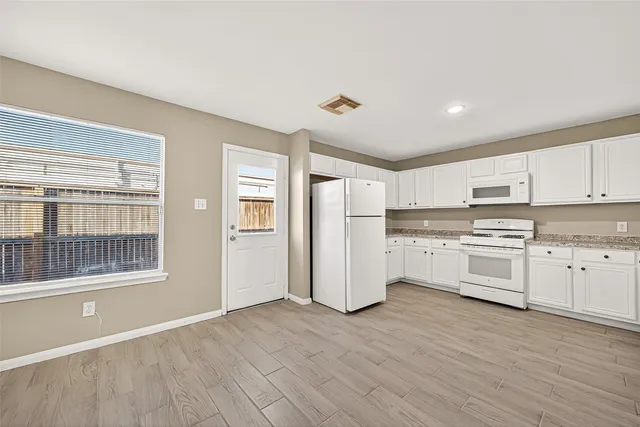 a kitchen with granite countertop white cabinets and white appliances