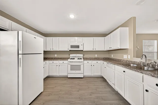 a kitchen with granite countertop white cabinets and refrigerator