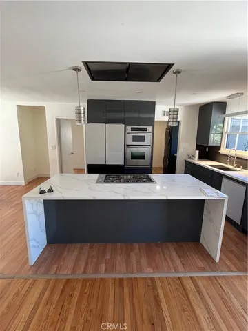 a large kitchen with kitchen island stainless steel appliances a stove cabinets and wooden floor