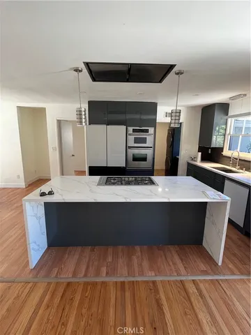 a large kitchen with kitchen island stainless steel appliances a stove cabinets and wooden floor