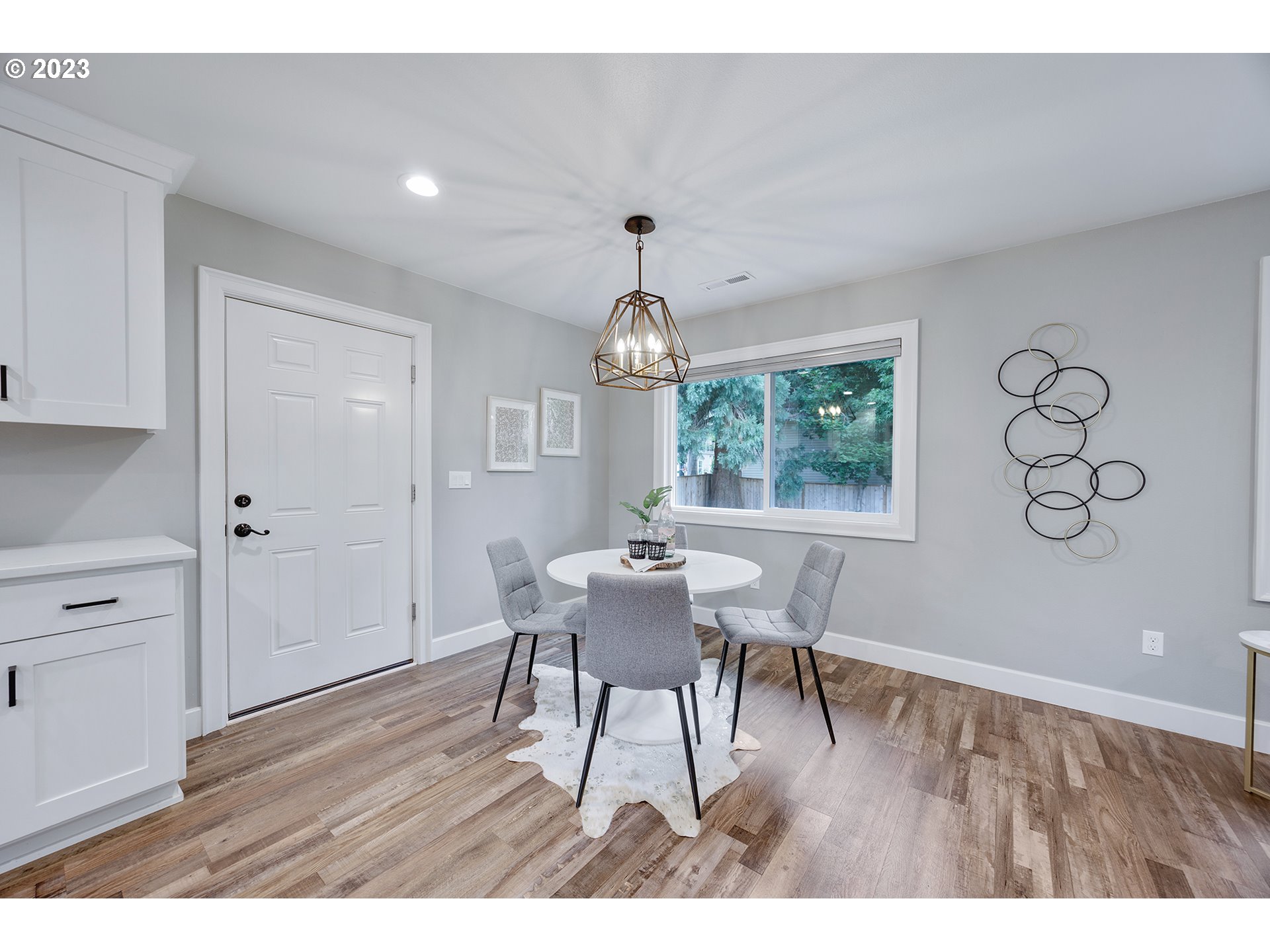 1427 Southeast 109th Avenue Portland, OR 97216 - Photo 12 of 44 a dining room with wooden floor a chandelier a wooden table and chairs