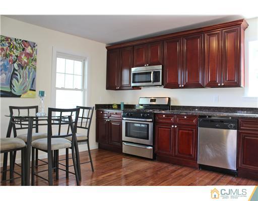 33 Meckes Street Springfield, NJ 07081 - Photo 8 of 25 a kitchen with stainless steel appliances granite countertop a stove top oven a sink dishwasher a dining table and chairs with wooden floor