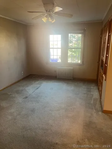 an empty room with windows and fan