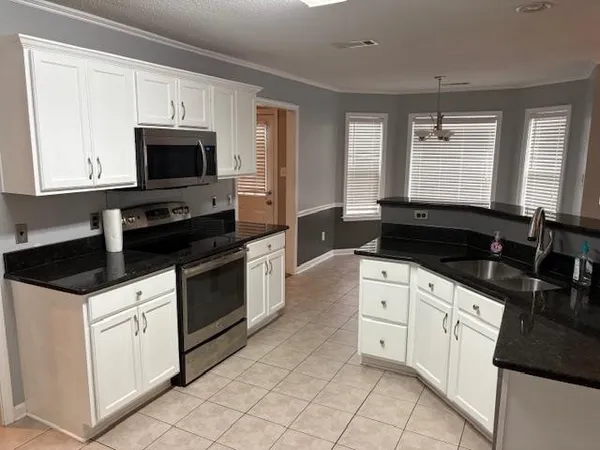 a kitchen with stainless steel appliances granite countertop white cabinets sink and window