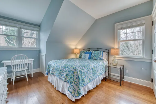 a bedroom with a bed a table and windows