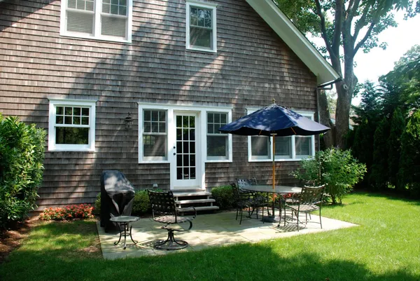 a view of a house with a yard chairs and table in a patio