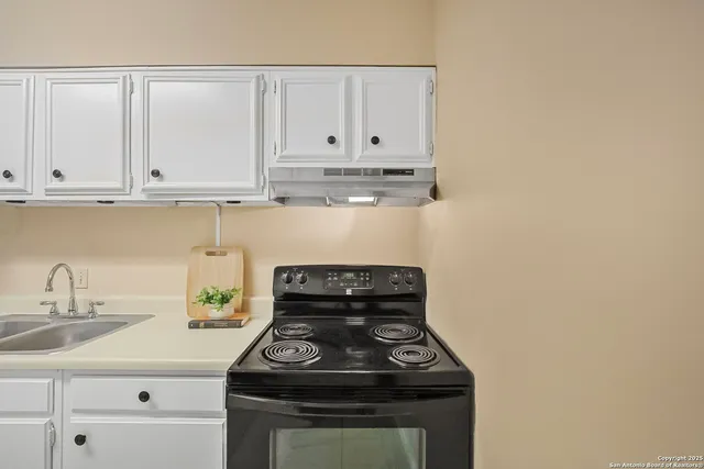 a kitchen with granite countertop white cabinets and a stove