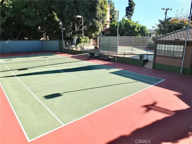 a view of a tennis ground with large trees