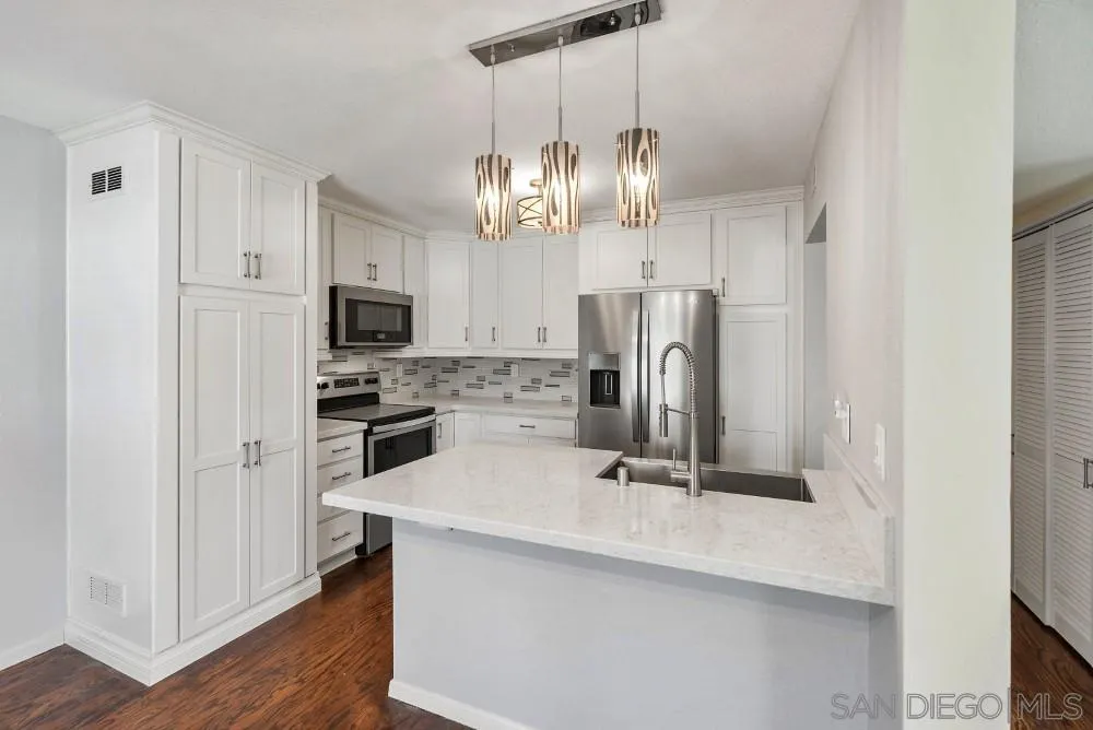219 Diamond Way, Unit 115 Vista, CA 92083 - Photo 15 of 36 a kitchen with stainless steel appliances a sink a refrigerator center island and cabinets