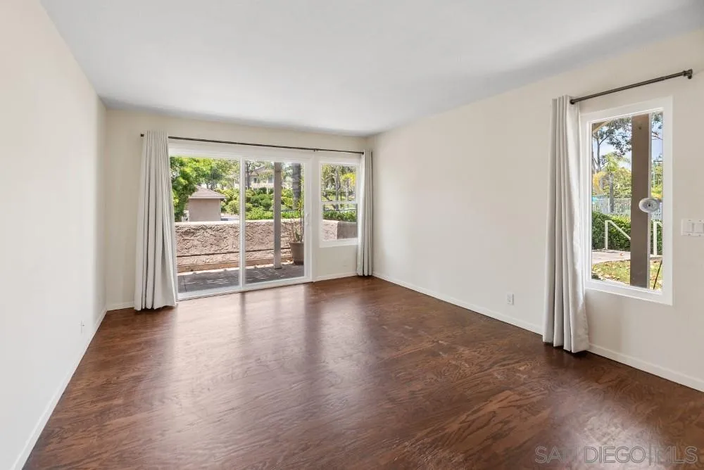 219 Diamond Way, Unit 115 Vista, CA 92083 - Photo 7 of 36 an empty room with wooden floor and windows