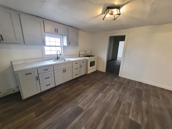 a large kitchen with a lot of white cabinets and wooden floor