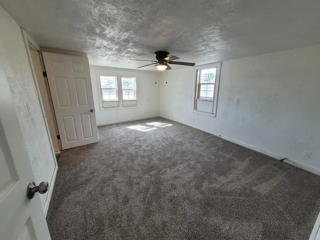 en empty room with windows and ceiling fan