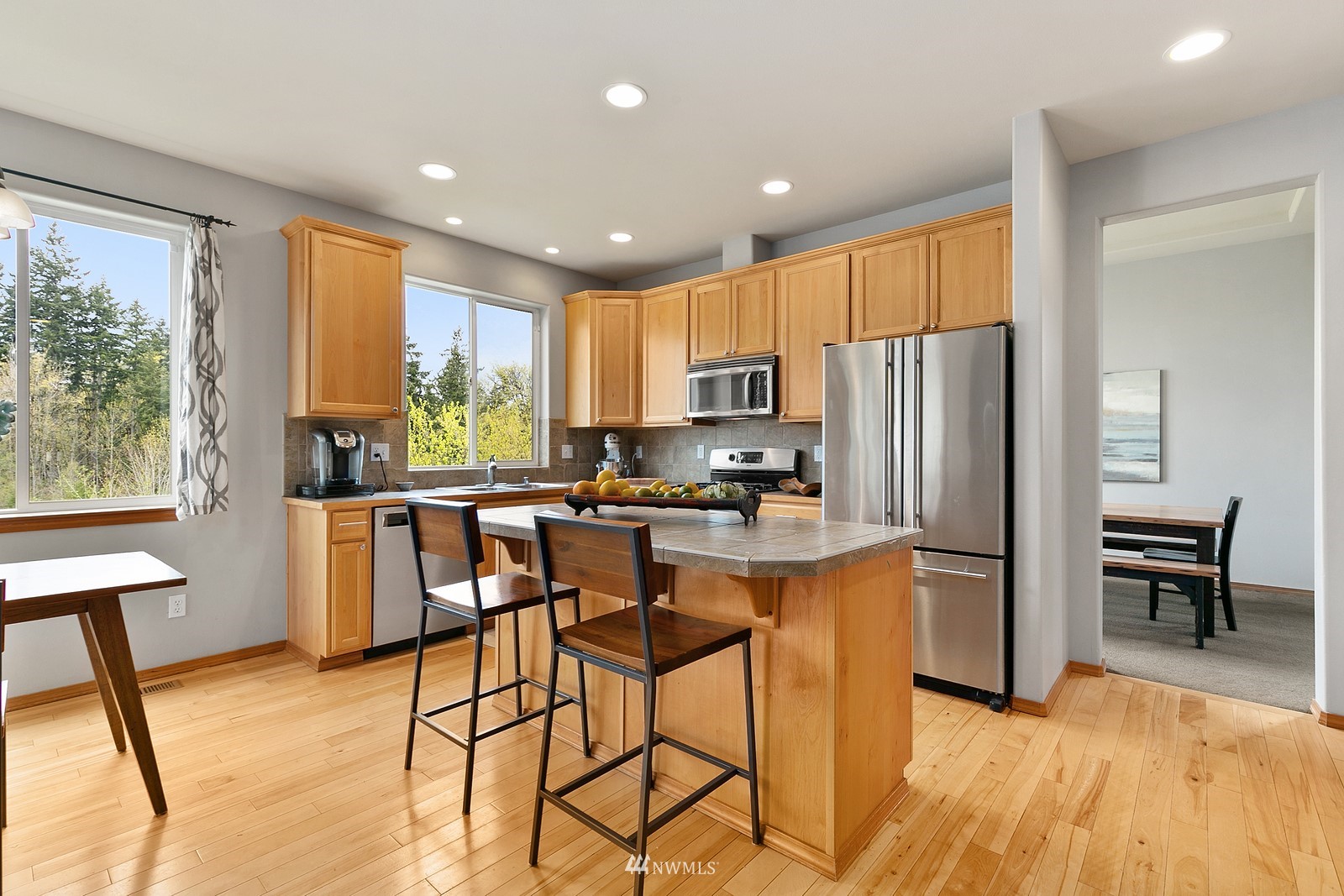 21117 Meridian Place West Bothell, WA 98021 - Photo 6 of 30 a kitchen with stainless steel appliances granite countertop a refrigerator a stove a sink a dining table and chairs with wooden floor