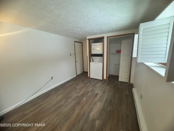 a view of an empty room with wooden floor and closet