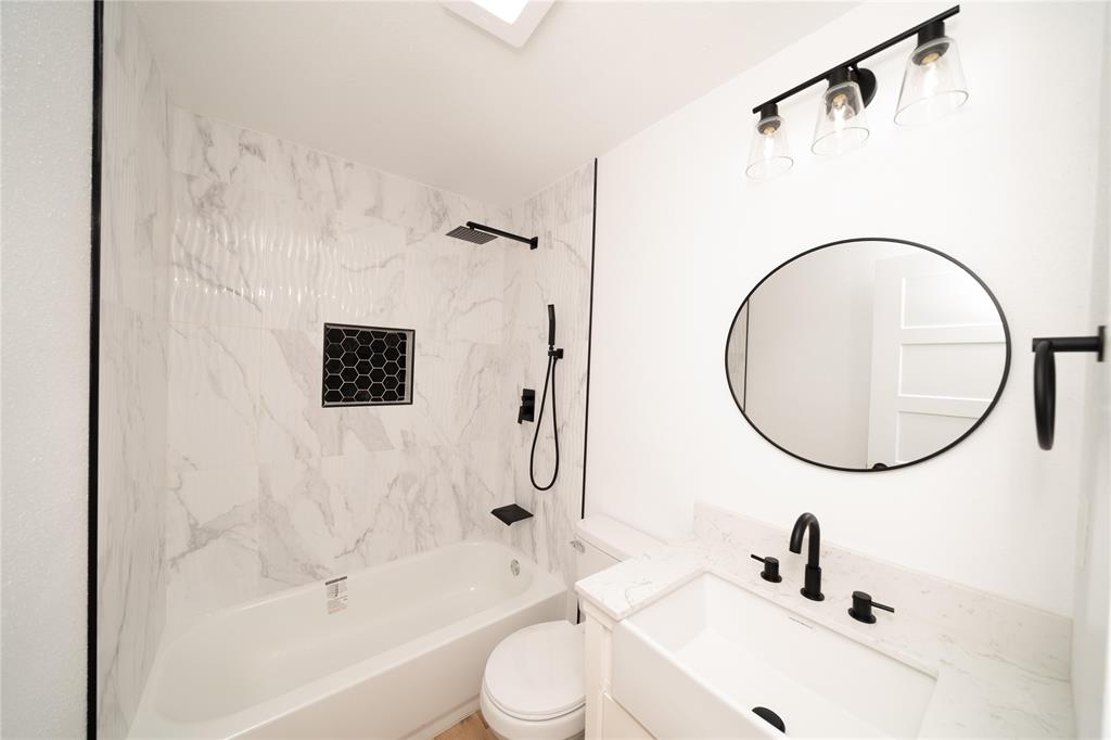 312 North Retta Street Fort Worth, TX 76111 - Photo 18 of 30 a bathroom with a sink a toilet and a mirror