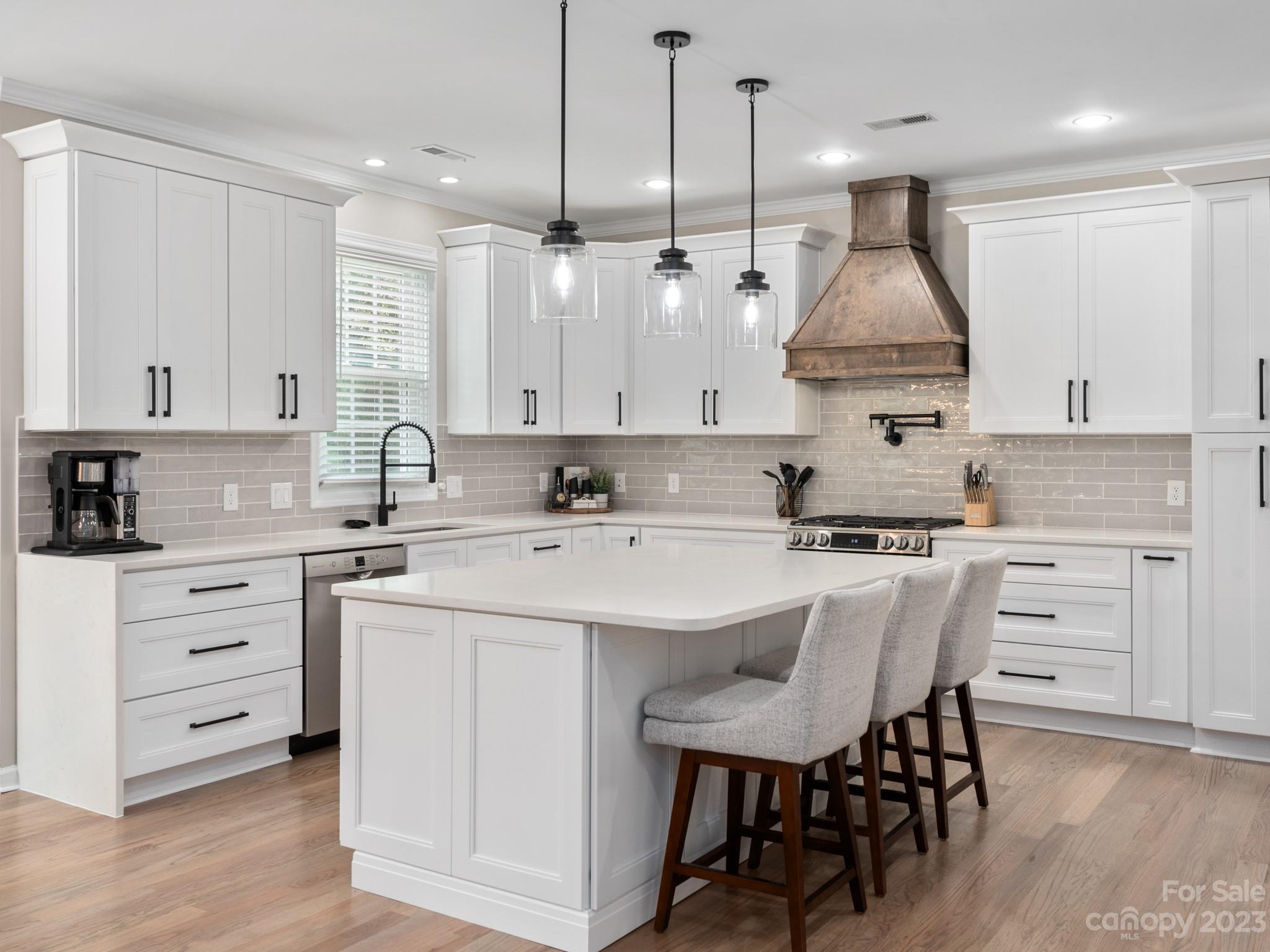 a kitchen with kitchen island a sink stove and white cabinets