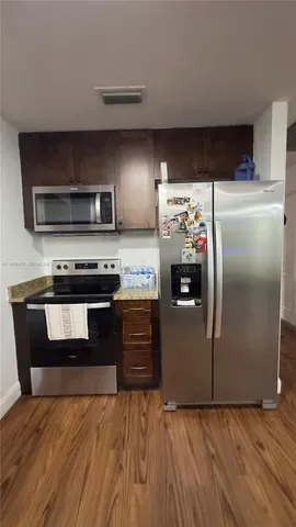 a kitchen with granite countertop a refrigerator and a stove top oven