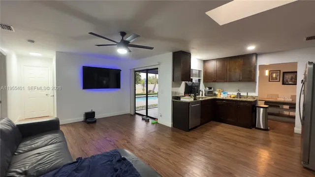 a large kitchen with stainless steel appliances kitchen island granite countertop a refrigerator a stove a sink dishwasher with wooden floor and cabinets