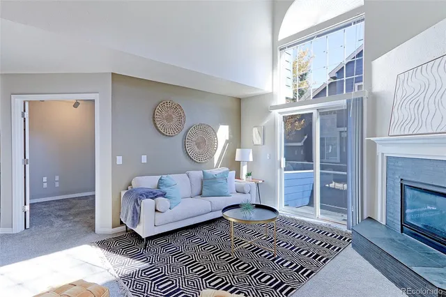a living room with furniture a fireplace and a large window