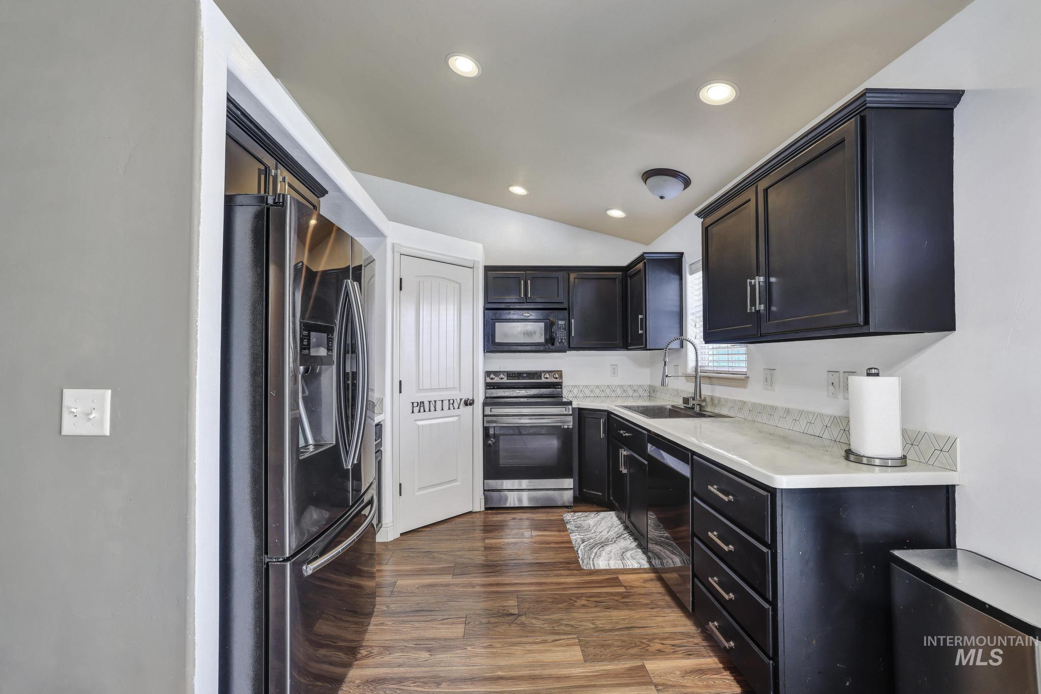 446 Noble Street Twin Falls, ID 83301 - Photo 8 of 42 Contemporary kitchen featuring dark wood cabinetry, stainless steel appliances, a white countertop, and wood-finish flooring