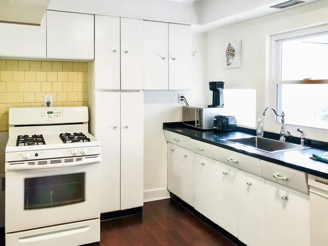 a kitchen with granite countertop white cabinets and white appliances
